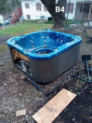 Hot tub before removal — blue spa sitting in a backyard, ready to be hauled away