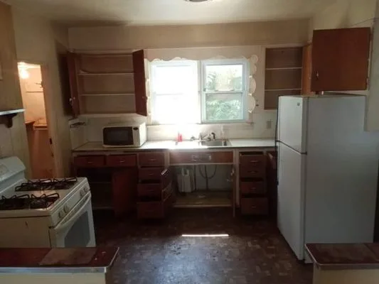 Kitchen before cleanout — empty cabinets, old appliances waiting for removal