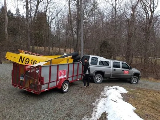 Cree loading debris onto the red trailer during a junk removal job